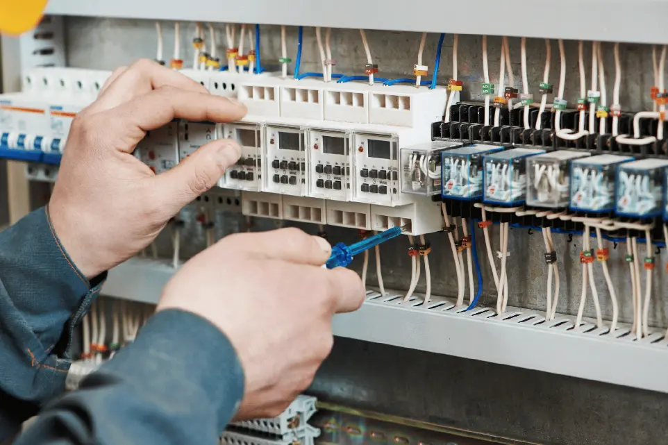 Detailaufnahme von Händen, die an elektrischen Schaltkreisen unSicherungen arbeiten.